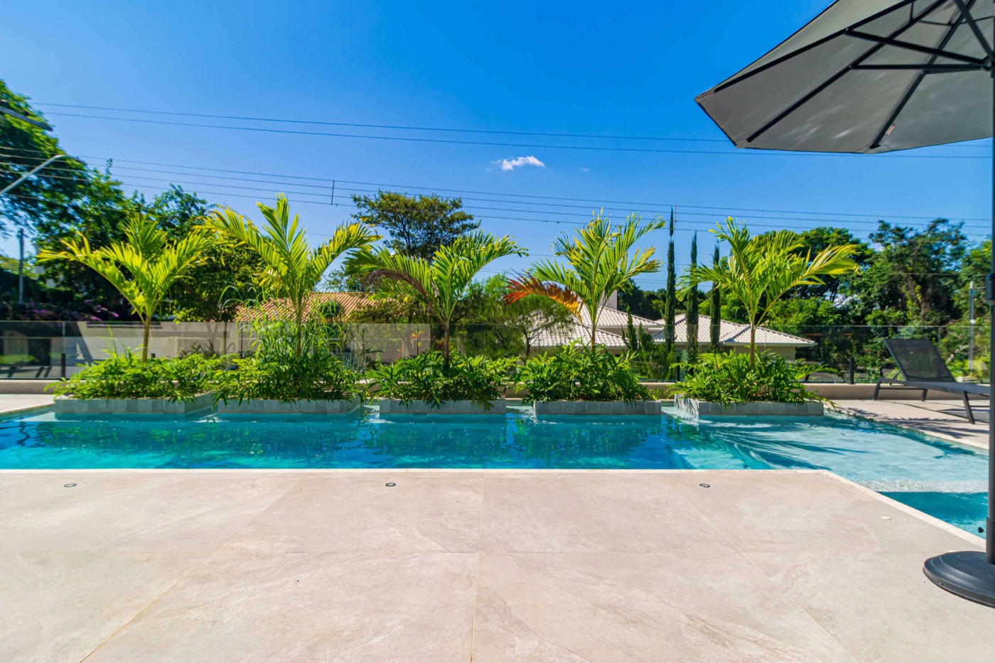 Piscina ampla com jardim tropical ao fundo