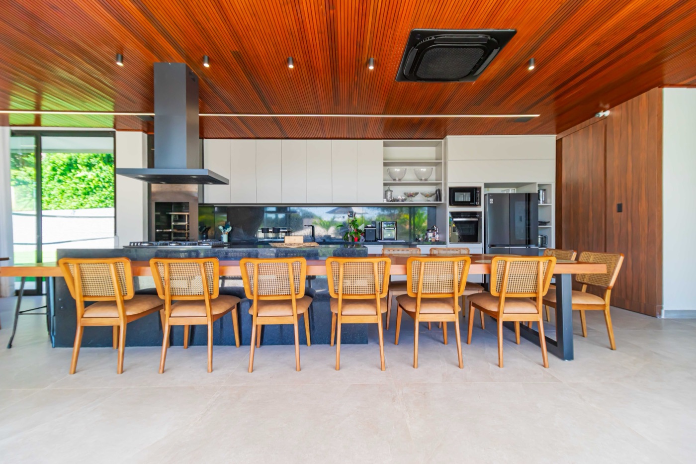 Cozinha gourmet com bancada em ilha e mesa de jantar longa
