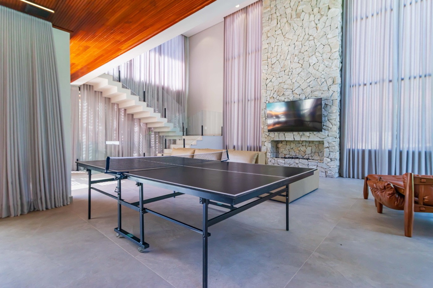 Salão de jogos com mesa de ping-pong e escada ao fundo