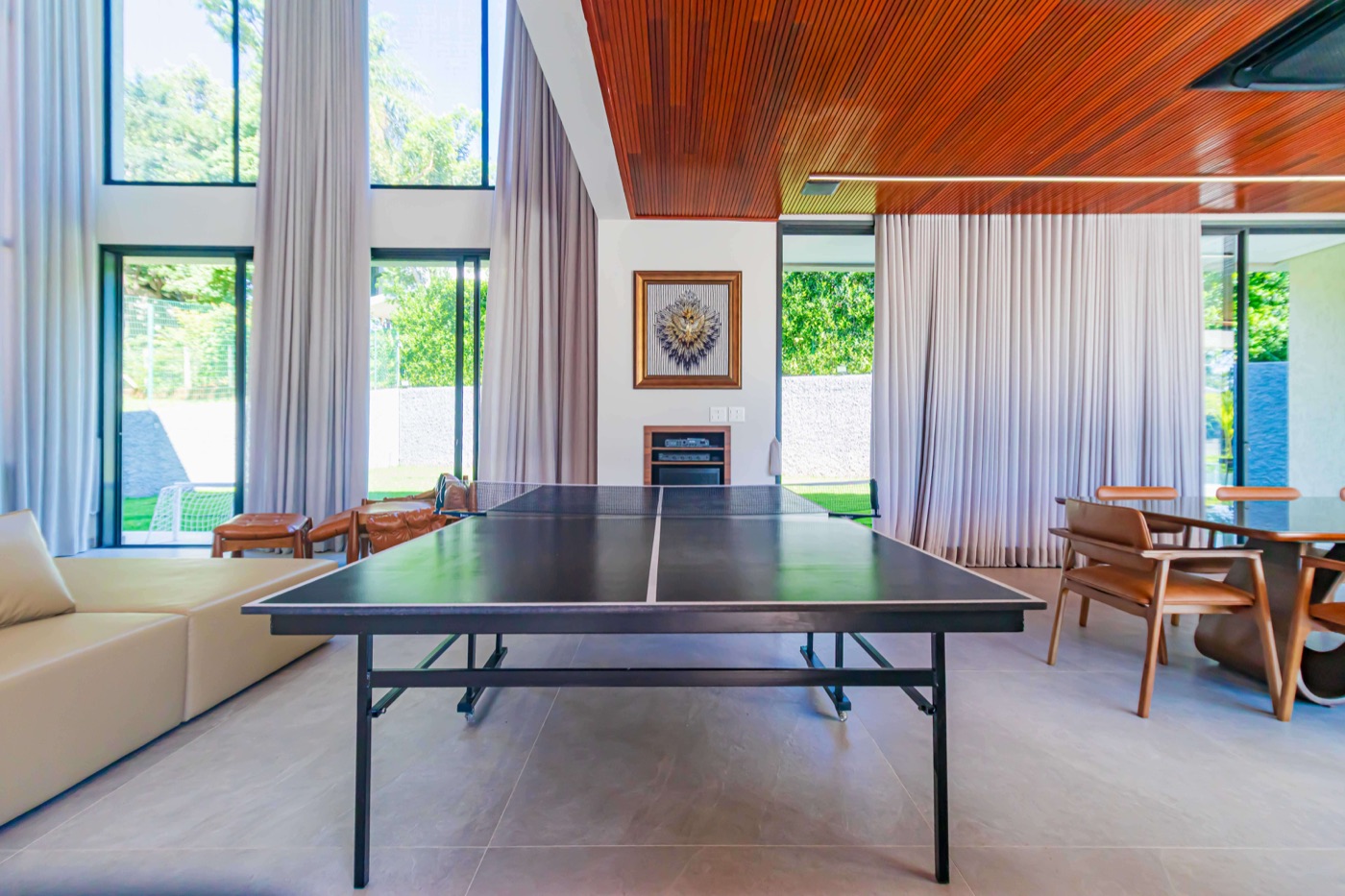 Sala de jogos com poltronas em couro e mesa de ping-pong