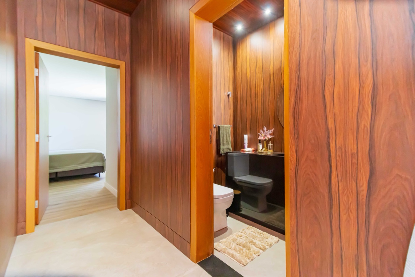 Corredor com painel em madeira levando ao lavabo